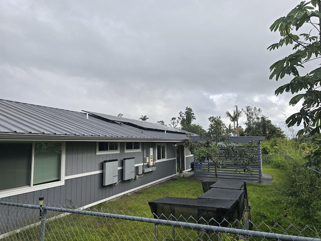 exterior space featuring roof mounted solar panels, fence, and metal roof