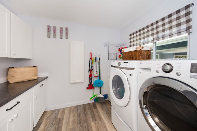 clothes washing area featuring separate washer and dryer, light hardwood / wood-style floors, and cabinets