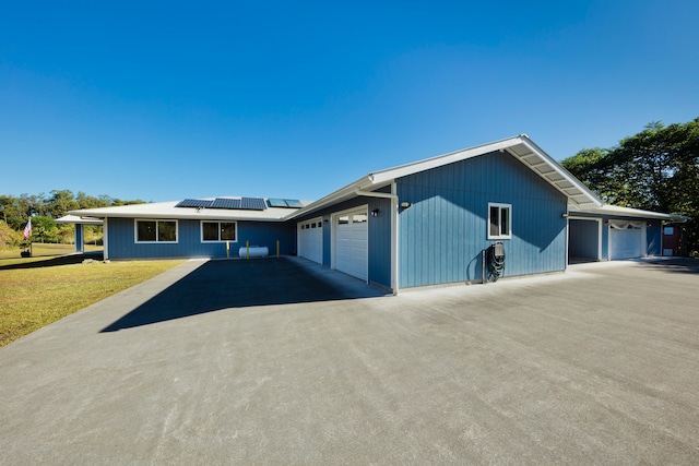 ranch-style house with a garage, a front yard, and solar panels