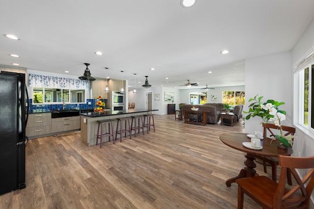 kitchen with a center island, light hardwood / wood-style flooring, double oven, black refrigerator, and a breakfast bar