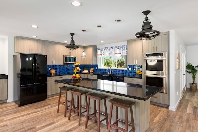 kitchen featuring a center island, backsplash, decorative light fixtures, black appliances, and light wood-type flooring