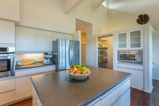 kitchen with white cabinets, a high ceiling, appliances with stainless steel finishes, and dark wood-type flooring