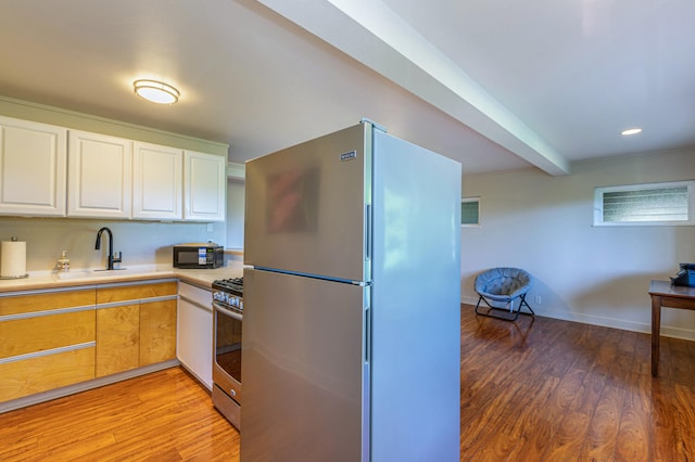 kitchen with refrigerator, gas stove, sink, light hardwood / wood-style flooring, and white cabinetry