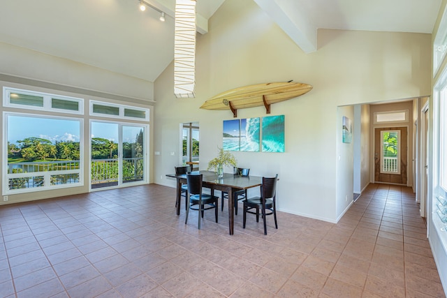 dining area with light tile patterned flooring, a towering ceiling, and beam ceiling