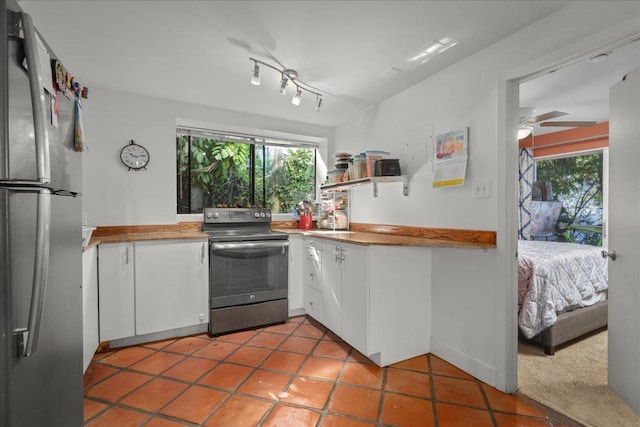 kitchen featuring tile patterned floors, stainless steel appliances, white cabinetry, and ceiling fan