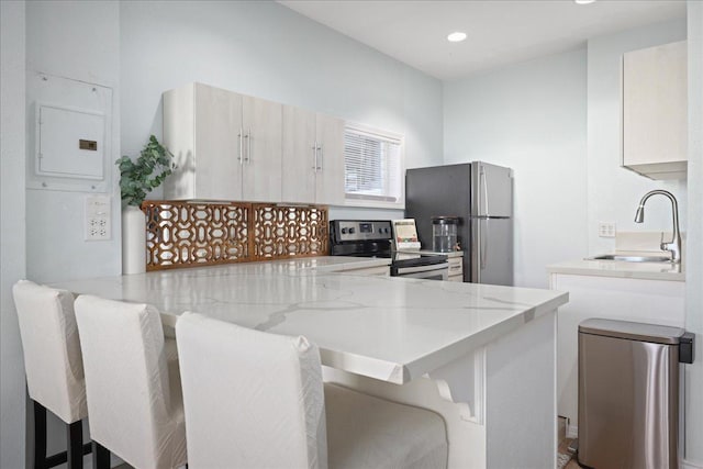 kitchen featuring a kitchen bar, kitchen peninsula, sink, and stainless steel appliances