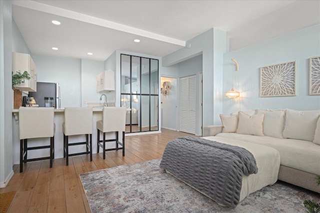 bedroom featuring stainless steel refrigerator, a closet, light hardwood / wood-style floors, and sink