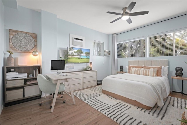 bedroom featuring a wall mounted AC, ceiling fan, and hardwood / wood-style flooring