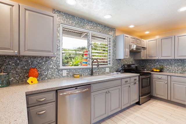 kitchen featuring gray cabinetry, sink, a textured ceiling, tasteful backsplash, and stainless steel appliances