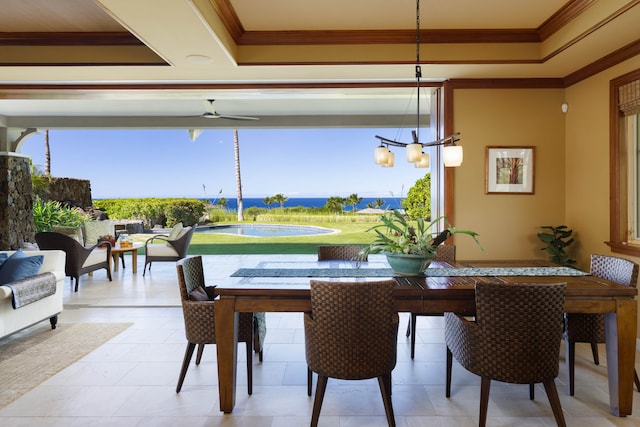 dining room with ceiling fan with notable chandelier, a water view, and crown molding