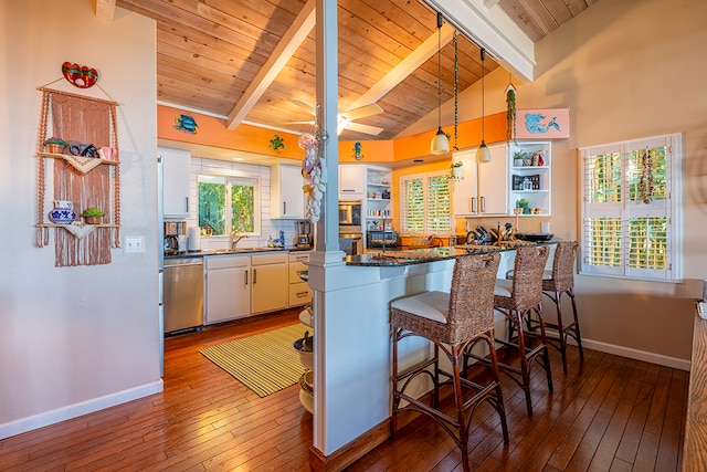 kitchen with vaulted ceiling with beams, white cabinets, stainless steel appliances, and decorative light fixtures