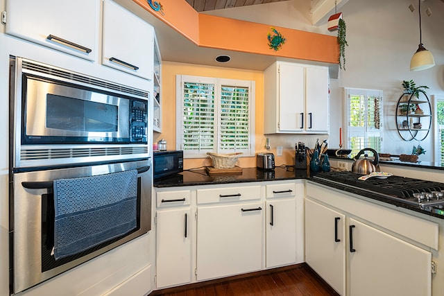 kitchen featuring lofted ceiling, dark wood-type flooring, white cabinets, hanging light fixtures, and appliances with stainless steel finishes