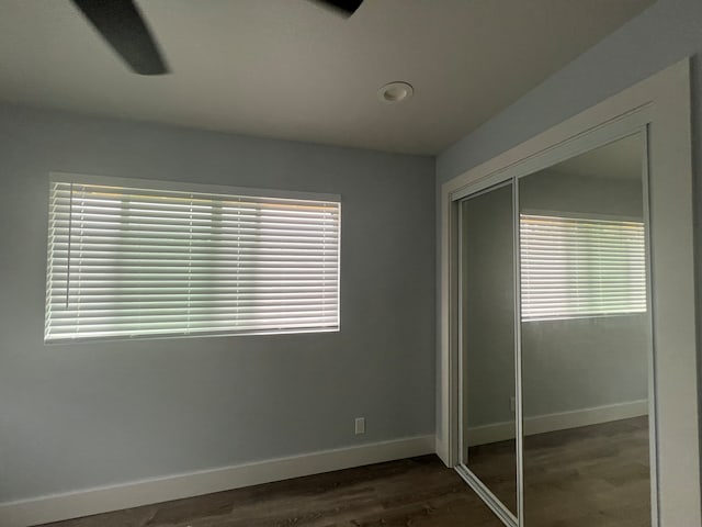 unfurnished bedroom with dark hardwood / wood-style floors, a closet, and ceiling fan