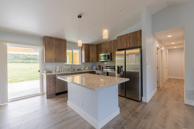 kitchen featuring appliances with stainless steel finishes, pendant lighting, light hardwood / wood-style flooring, a kitchen island, and lofted ceiling