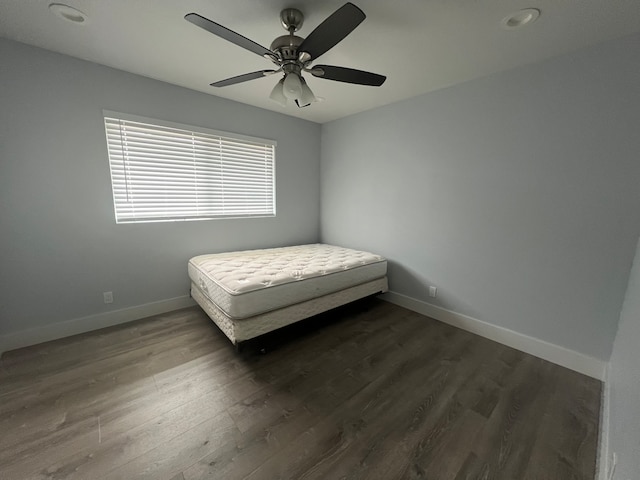 unfurnished bedroom featuring ceiling fan and dark wood-type flooring