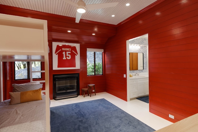 unfurnished living room with ceiling fan, plenty of natural light, wood walls, and sink