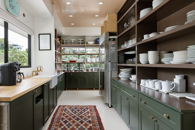 bar with sink, high quality fridge, and green cabinetry