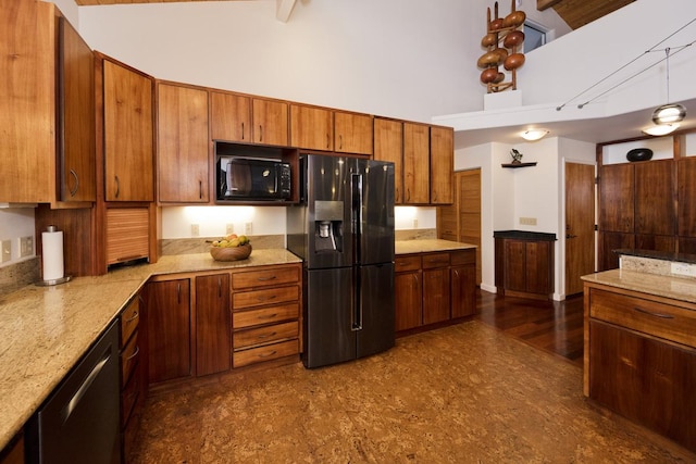 kitchen with beam ceiling, light stone counters, a towering ceiling, and stainless steel appliances