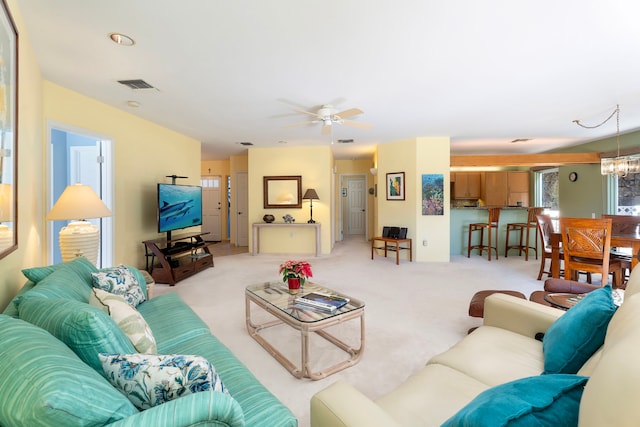 carpeted living room featuring ceiling fan with notable chandelier