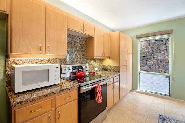 kitchen with electric range, light tile patterned flooring, backsplash, and dark stone counters