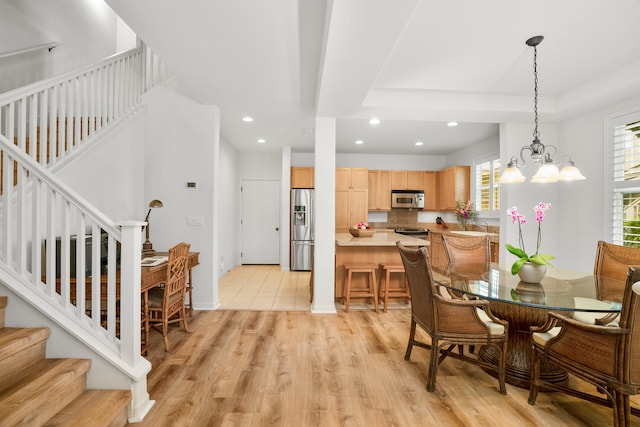 dining area with light hardwood / wood-style floors and a chandelier