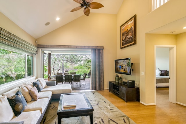 living room with high vaulted ceiling, ceiling fan, light wood-type flooring, and a wealth of natural light