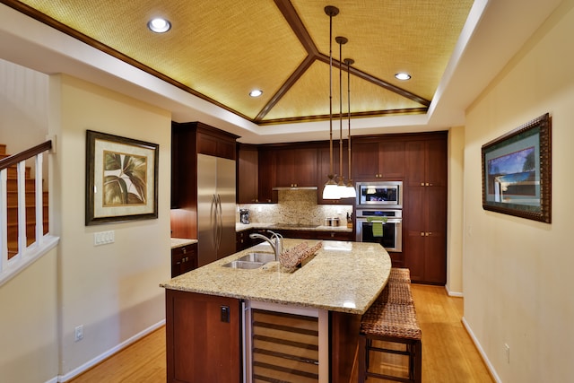 kitchen featuring decorative light fixtures, sink, wine cooler, and an island with sink