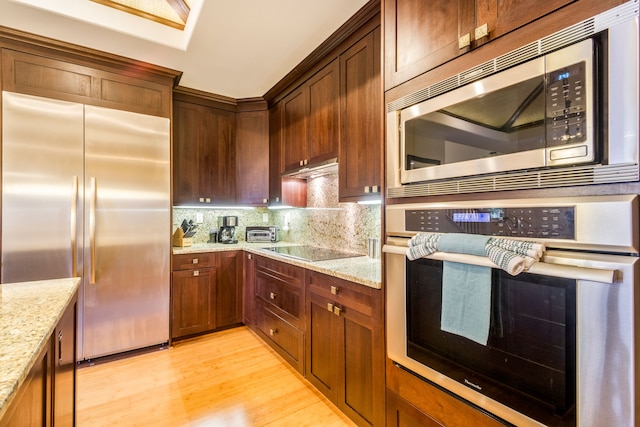 kitchen featuring tasteful backsplash, light stone countertops, stainless steel appliances, and light hardwood / wood-style floors