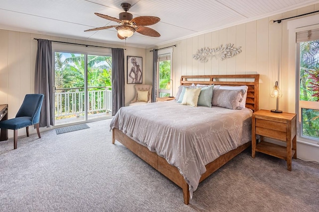 carpeted bedroom featuring ceiling fan, wood walls, access to exterior, and crown molding