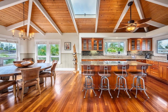 kitchen featuring a breakfast bar, a kitchen island, light stone countertops, and wood-type flooring