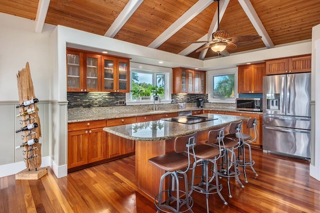 kitchen with appliances with stainless steel finishes, sink, vaulted ceiling with beams, dark hardwood / wood-style floors, and a kitchen island