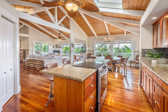 kitchen with a breakfast bar, a wealth of natural light, a kitchen island, and stainless steel electric stove