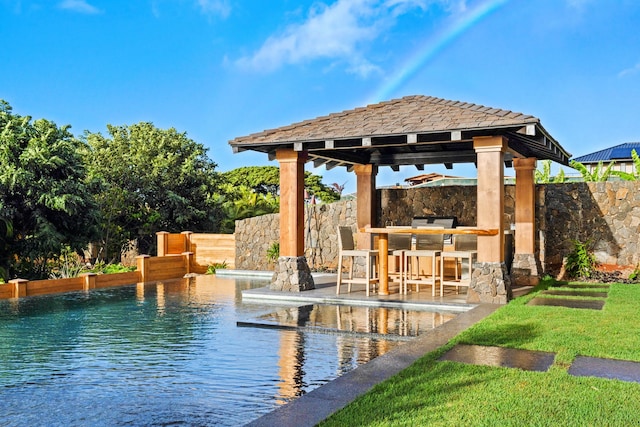 view of swimming pool with area for grilling, a water view, an outdoor bar, and a gazebo