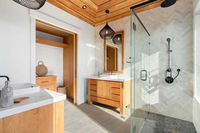 bathroom with a shower with door, vanity, and tile patterned flooring