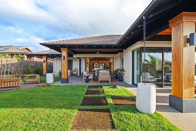 back of house with outdoor lounge area, a yard, and a patio