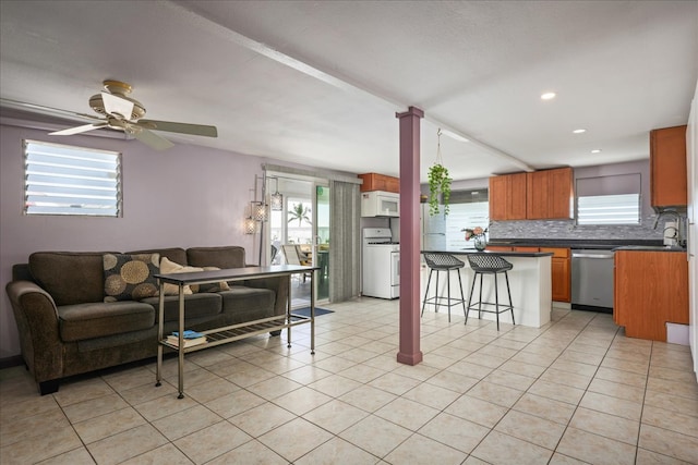 interior space with decorative backsplash, a kitchen bar, white appliances, ceiling fan, and sink