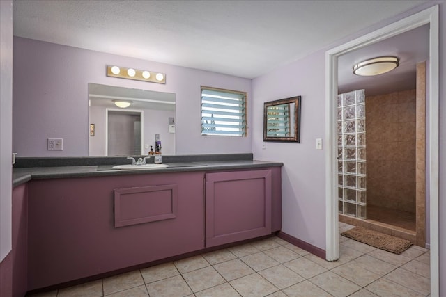 bathroom featuring tile patterned flooring, vanity, tiled shower, and a textured ceiling