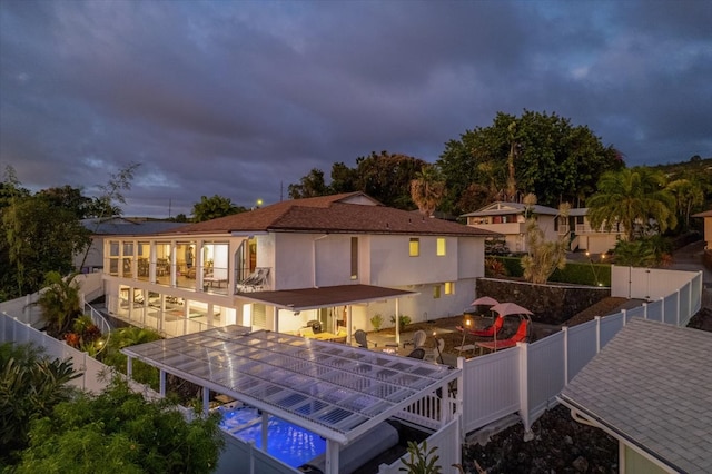 back house at dusk featuring a balcony and a patio area