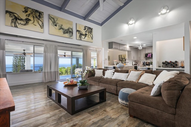 living room with beam ceiling, high vaulted ceiling, and light hardwood / wood-style floors