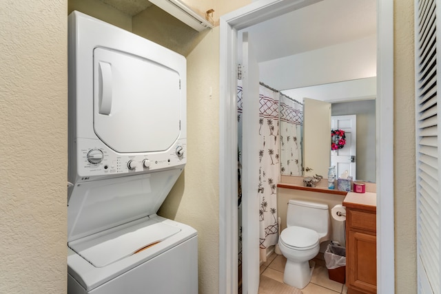 laundry room featuring stacked washer and clothes dryer and light tile patterned flooring