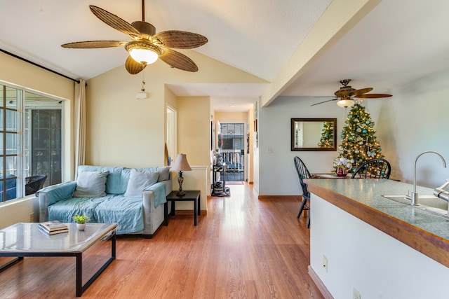 living room with light hardwood / wood-style flooring, vaulted ceiling, and sink