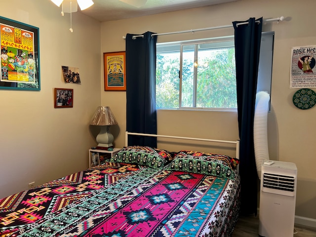 bedroom with heating unit, ceiling fan, and hardwood / wood-style floors