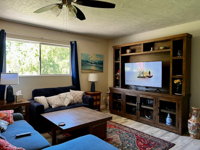 living room with a textured ceiling, light hardwood / wood-style flooring, and ceiling fan