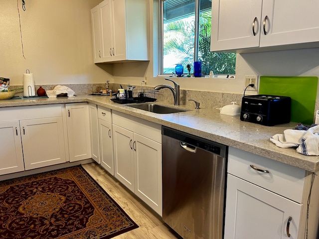 kitchen with sink, stainless steel dishwasher, light stone countertops, light wood-type flooring, and white cabinetry