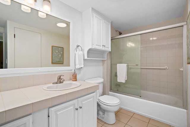 full bathroom featuring tile patterned floors, toilet, vanity, and combined bath / shower with glass door