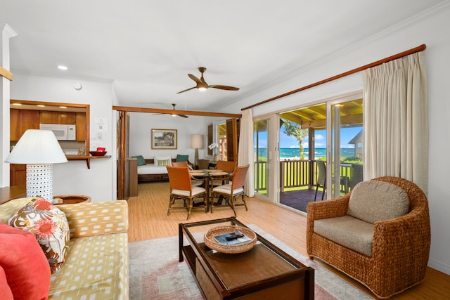 living room with ceiling fan, light wood-type flooring, and crown molding