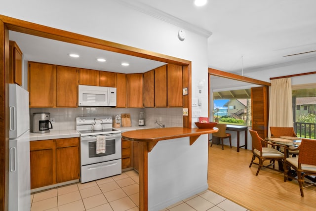 kitchen featuring tasteful backsplash, crown molding, white appliances, and a kitchen breakfast bar