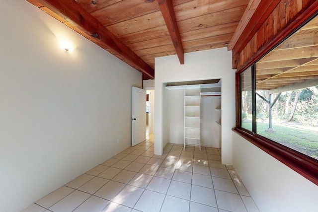 unfurnished bedroom with beam ceiling, a closet, wooden ceiling, and light tile patterned flooring