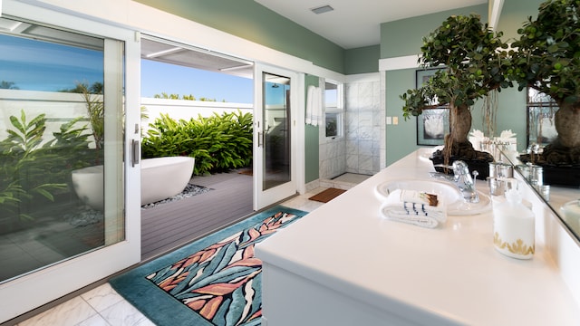 bathroom with vanity, a bathtub, and french doors