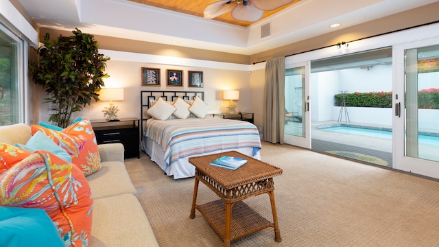 bedroom with light carpet, access to outside, ceiling fan, and a tray ceiling